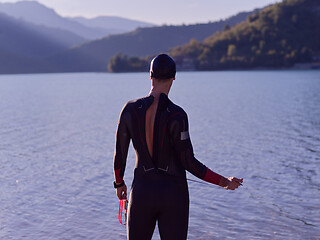 Image showing authentic triathlon athlete getting ready for swimming training on lake