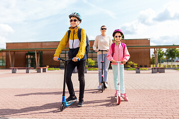 Image showing happy school children with mother riding scooters