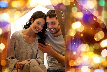 Image showing happy couple with smartphone in kids tent at home