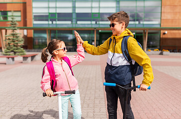 Image showing school kids riding scooters and making high five