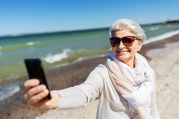 Image showing senior woman taking selfie by smartphone on beach