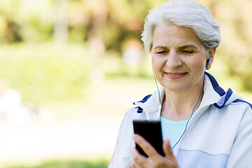 Image showing sporty senior woman with earphones and smartphone