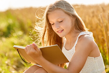 Image showing smiling girl writing to diary on cereal field