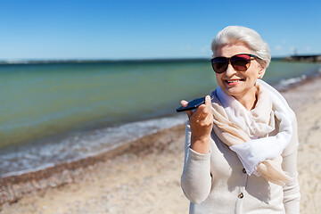 Image showing old woman recording voice by smartphone on beach