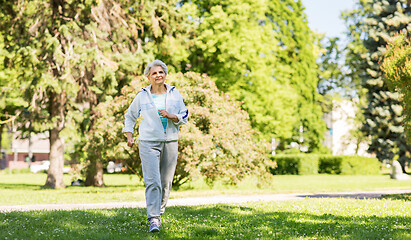 Image showing senior woman running along summer park