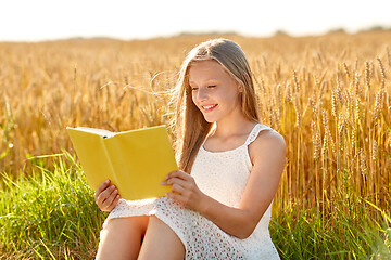 Image showing smiling young girl reading book on cereal field