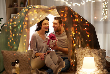 Image showing happy couple with gift box in kids tent at home