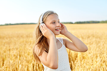 Image showing happy girl in headphones on cereal field in summer