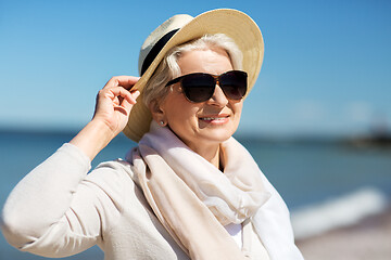 Image showing happy senior woman in sunglasses and hat on beach