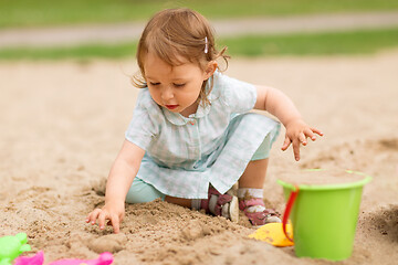 Image showing little baby girl plays with toys in sandbox