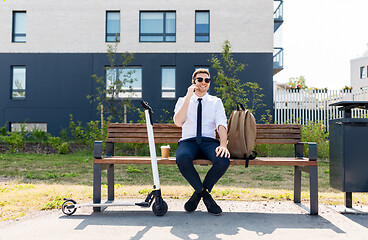 Image showing businessman with scooter calling on smartphone