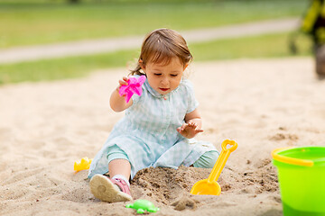 Image showing little baby girl plays with toys in sandbox