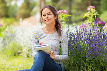 Image showing young woman writing to notebook at summer garden