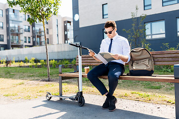 Image showing businessman with file and scooter sitting on bench