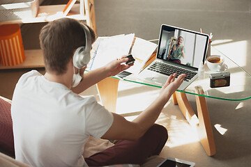 Image showing Man working from home, remote office concept. Young businessman, manager doing tasks with laptop, has online conference.