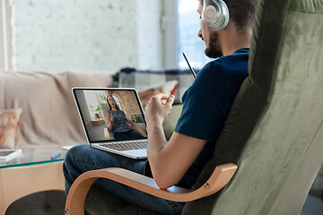 Image showing Man working from home, remote office concept. Young businessman, manager doing tasks with laptop, has online conference.