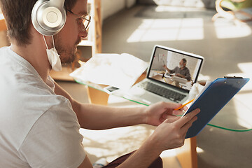 Image showing Man working from home, remote office concept. Young businessman, manager doing tasks with laptop, has online conference.