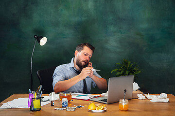 Image showing Ill young man with fever and cold looks suffering at home