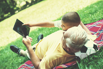 Image showing grandfather and child in park using tablet