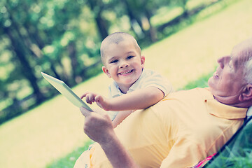 Image showing grandfather and child in park using tablet