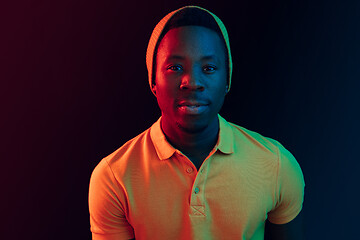 Image showing Portrait of a happy young african american man smiling on black neon background