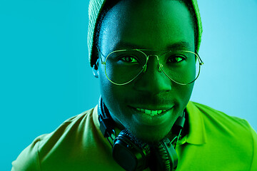 Image showing Portrait of a happy young african american man smiling on black neon background