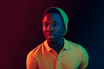 Image showing Portrait of a happy young african american man smiling on black neon background