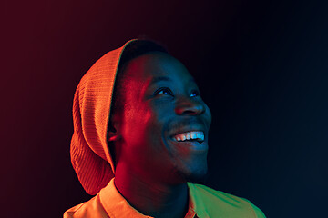 Image showing Portrait of a happy young african american man smiling on black neon background