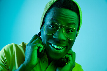 Image showing Portrait of a happy young african american man smiling on black neon background