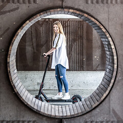 Image showing Casual caucasian teenager riding urban electric scooter in urban environment. Urban mobility concept