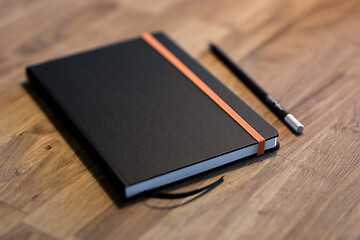 Image showing Black business notebook and regular pencil on a vintage wooden desk