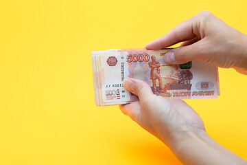 Image showing Two hands holding a crustacean of five thousandth Russian rubles on a yellow background