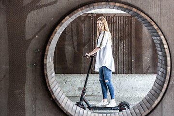 Image showing Casual caucasian teenager riding urban electric scooter in urban environment. Urban mobility concept