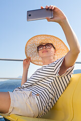 Image showing Beautiful, romantic blonde woman taking selfie self portrait photo on summer vacations traveling by cruse ship ferry boat.