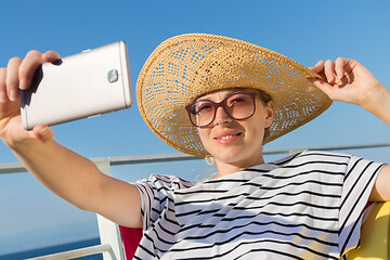 Image showing Beautiful, romantic blonde woman taking selfie self portrait photo on summer vacations traveling by cruse ship ferry boat.