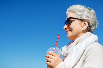 Image showing senior woman drinking orange juice outdoors