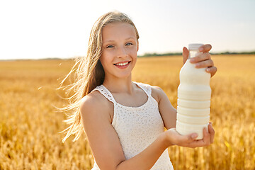 Image showing happy girl with bottle of milk on cereal field