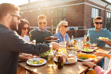 Image showing happy friends eating at barbecue party on rooftop