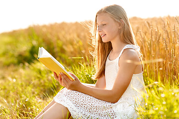 Image showing smiling young girl reading book on cereal field