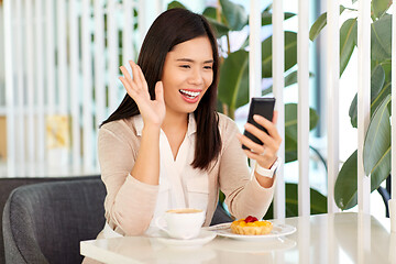 Image showing woman having video call on smartphone at cafe