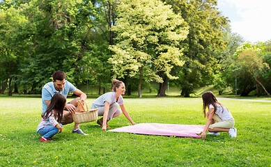 Image showing family laying down picnic blanket in summer park