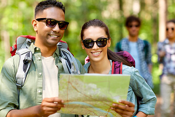 Image showing friends with map and backpacks hiking in forest