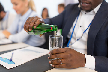 Image showing businessman pouring water to glass at conference