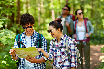 Image showing friends with map and backpacks hiking in forest