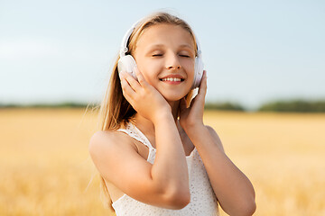 Image showing happy girl in headphones on cereal field in summer