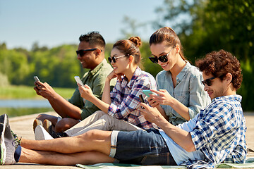 Image showing friends with smartphone on lake pier in summer