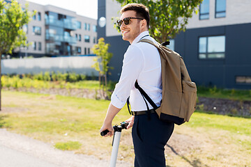 Image showing businessman with backpack riding electric scooter