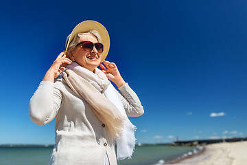 Image showing happy senior woman in sunglasses and hat on beach