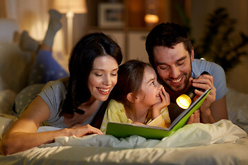 Image showing happy family reading book in bed at night at home