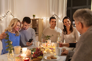 Image showing happy couple with smartphone at family tea party